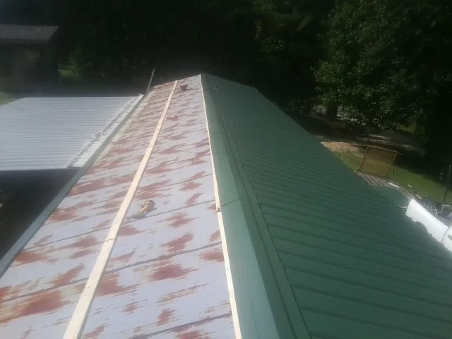 Old rusted panels beside newly installed green metal roofing — Wind Damage Roof Repair by Roofing Brothers in Lansford
