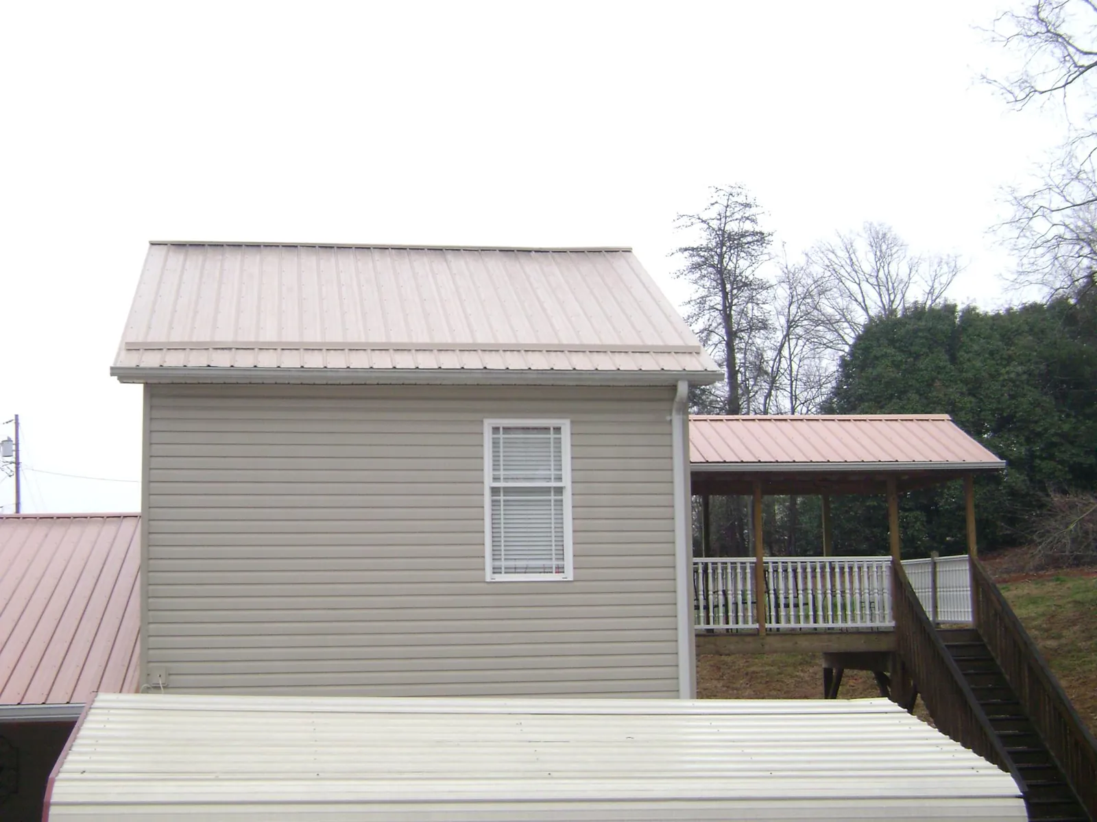 Tan metal roofs on a two story addition and attached porch, from a Roof Replacement job in Lansford