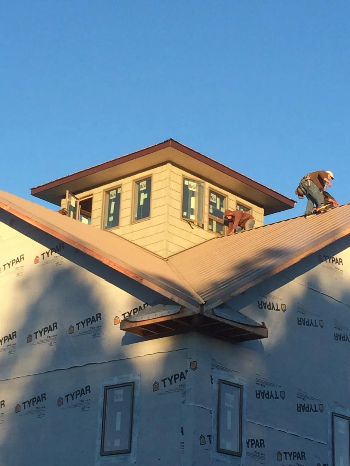 Roofers working around a rooftop cupola on a new metal roof at sunset — Roof Waterproofing in Lansford by Roofing Brothers